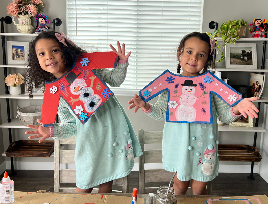 Young kids holding up their finished cardboard sweaters