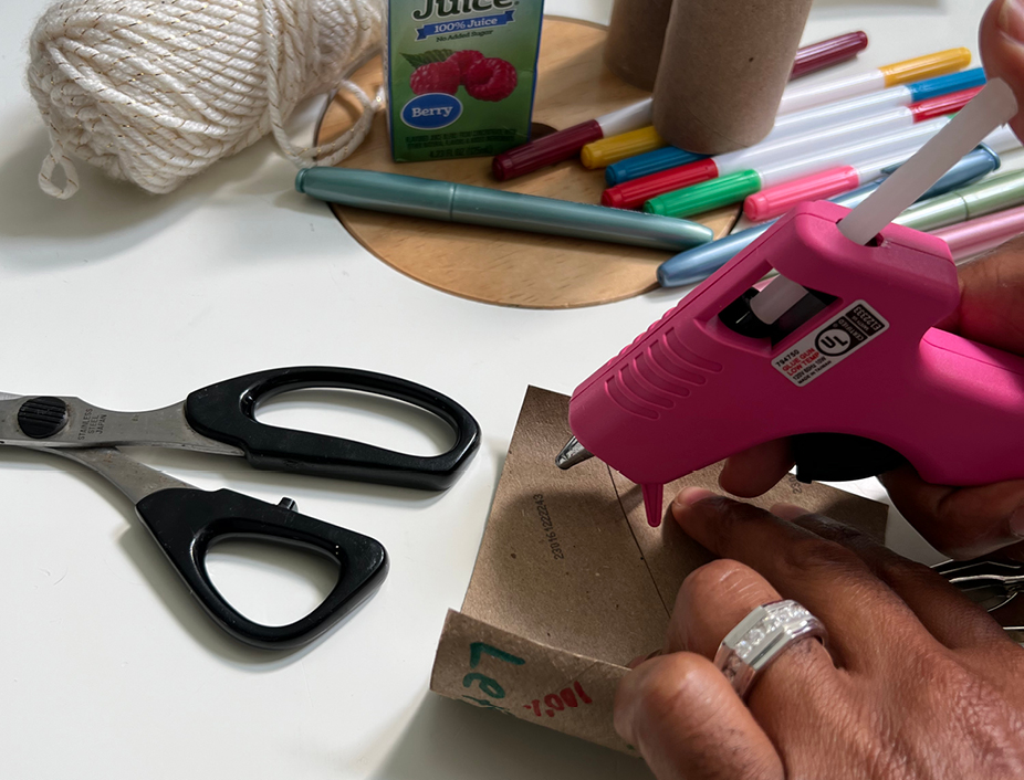 adult using a hot glue gun to build the binoculars