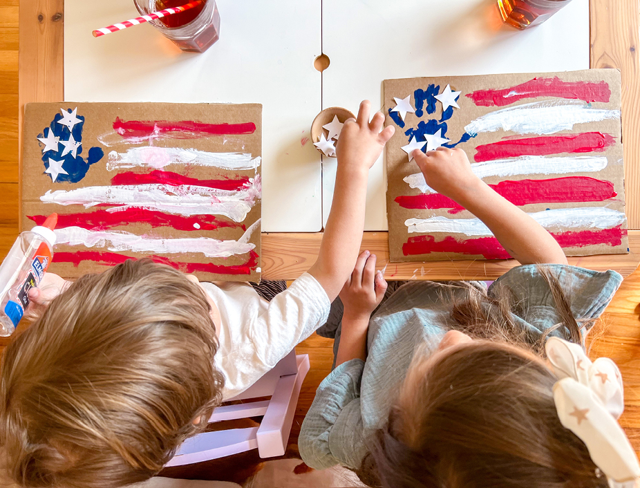 putting the white cut out paper stars on the cardboard flag