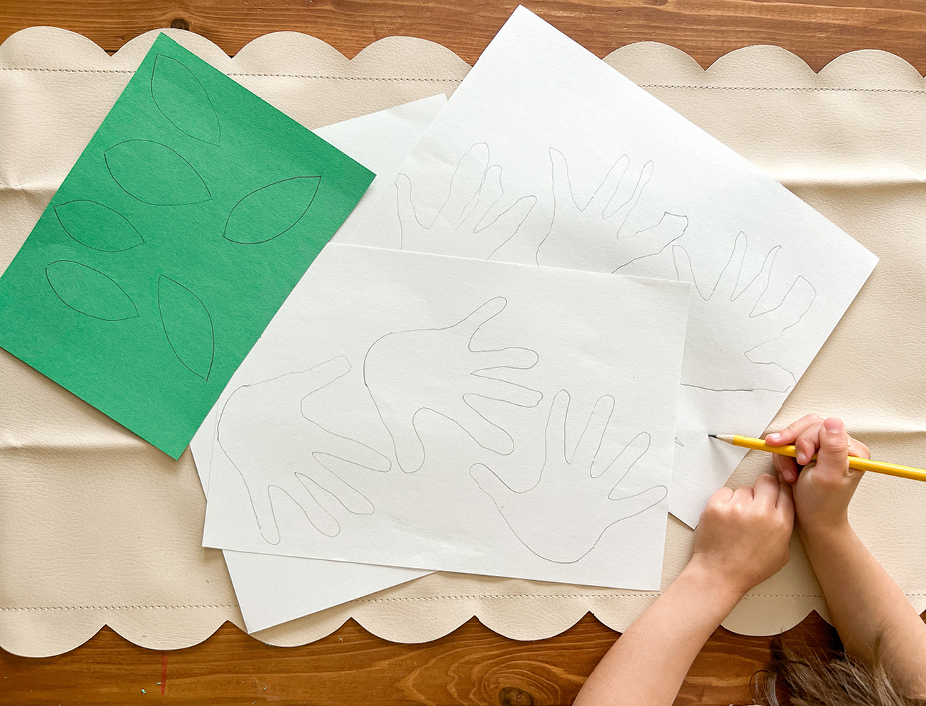 hands traced on white paper and leaves drawn on the green