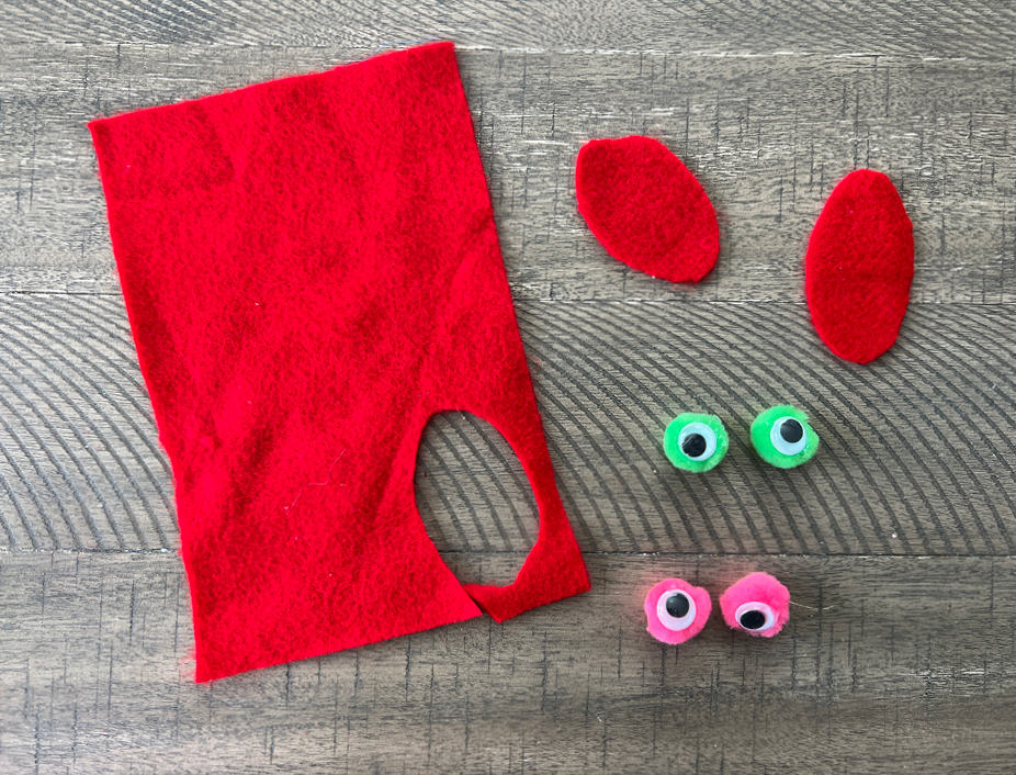 Crafting: Cutting a tongue shape from felt material and gluing googly eyes to pom pom balls.